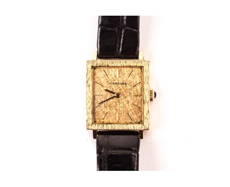 An 18ct gold cased Garrard lady’s wristwatch, having rectangular textured bezel and gilt dial with baton numerals, on a black