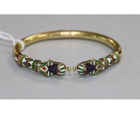 An Egyptianesque yellow metal, enamel and gem set hinged bangle.