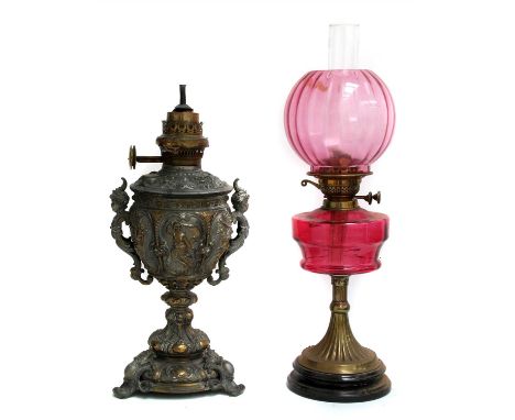 A Victorian oil lamp , with a cranberry glass reservoir and shade, 63cm high overall and a cast white metal oil lamp, 55cm hi