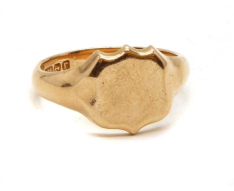 A 9ct rose gold signet ring, with a shield shaped head to tapered shoulders and a plain shank, Birmingham 1916, 7.60g Finger 