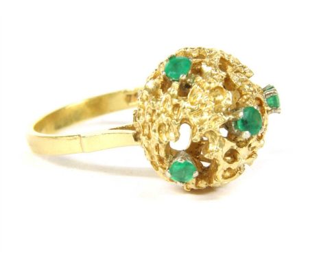 An Italian 18ct gold emerald ring, c.1960, the circular domed head of openwork abstract modernist design, four claw set with 