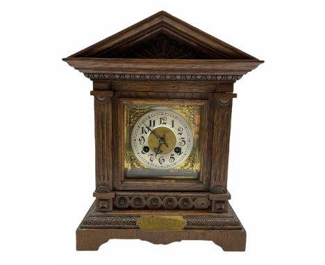 An early twentieth century German oak mantle clock in an architectural case on a shaped plinth with egg and dart moulding, th