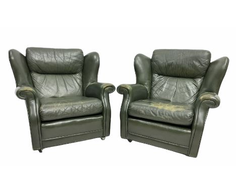 Pair of vintage green leather wing back armchairs, with loose cushions, raised on castors, W94cm