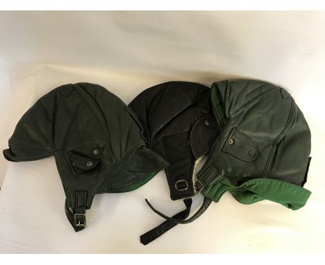 Two green leather flying helmets by Aeronautica, both large and a black leather and faux sheepskin lined flying helmet. 