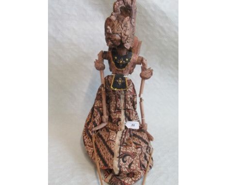 A Balinese carved and painted stick puppet in decorative ethnic dress.