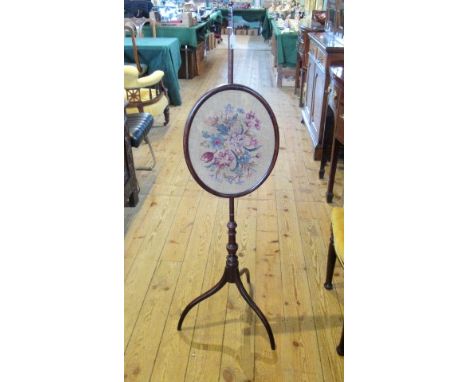 An early 19th century mahogany pole screen, supporting a later wool work tapestry panel in an oval frame, the whole on three 