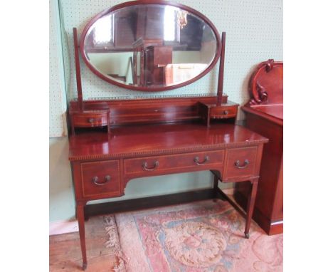 An Edwardian mahogany ebony and boxwood banded dressing table, having a bevelled oval adjustable mirror above trinket shelf a