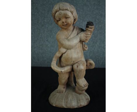 A carved cherub holding the charred remains of a torch or lantern. H.46 cm. 