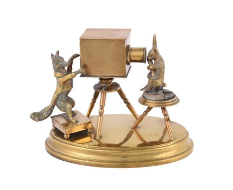 A novelty brass inkwell, late 19th/early 20th century, the inkwell modelled as a box camera operated by an anthropomorphic fo