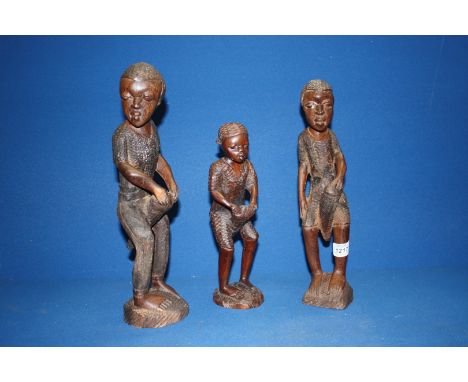Three graduated carved African male figures playing Bongo drums