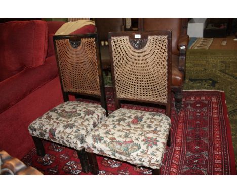 A pair of late Victorian low Hall Chairs, cane back with carved fleur-de-lys motif, and having tapestry pattern seats, standi