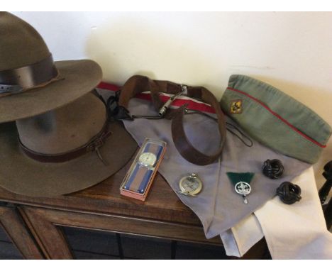 A collection of American Scouts equipment including three hats, badges, compass, wrist compass, two belts with whistle, cap a