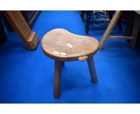 An Arts and Crafts golden oak three legged stool by 'Mouseman' Thompson, having typical carved mouse motif to rim