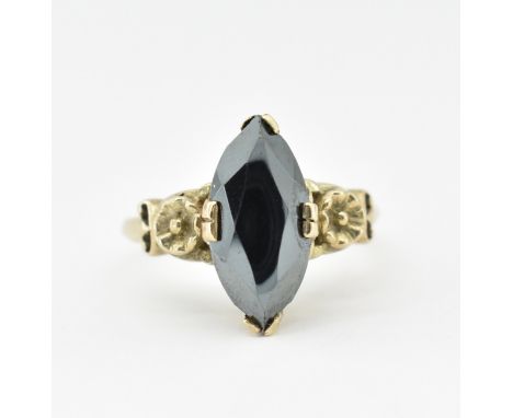 A 9ct gold and hematite dress ring. The ring set with a marquise cut hematite having floral stylised shoulders to plain shank