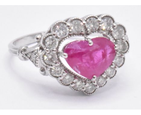 An 18ct white gold ring and diamond heart ring. The central heart shaped faced cut ruby stone within a halo of diamonds set t