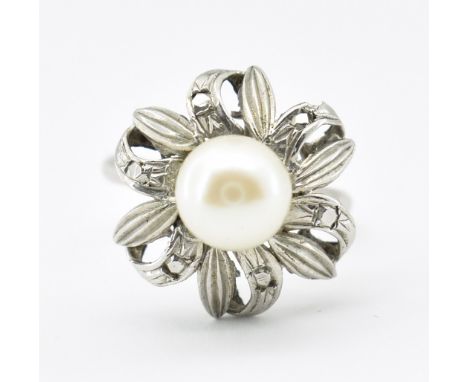 An 18ct white gold and pearl ring. The ring set with an off round pearl set within a flower head mount to plain band. Marked 