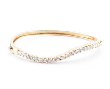 An 18ct gold and diamond bangle bracelet. The bracelet having a row of twenty five round cut diamonds with tongue and groove 