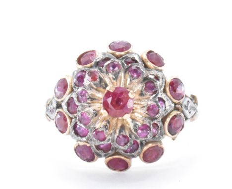 An 18ct gold and ruby cluster ring. The ring having a floral domed head set with round cut rubies. Shank marked 18k. Weight 5