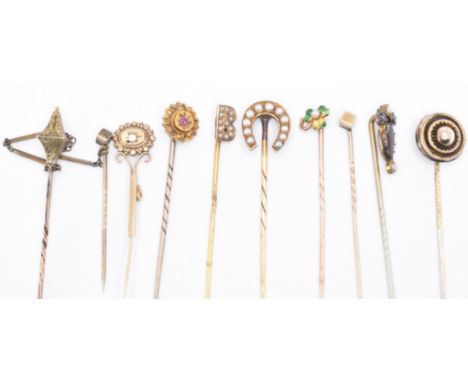 A collection of gold and yellow metal stick pins. A pearl set horse shoe, a roundel, a ruby set star marked 15ct, an articula