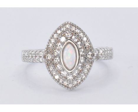 A silver and CZ ring having a central marquise cut opal cabochon surrounded by halos of cubic zirconia with a further accent 