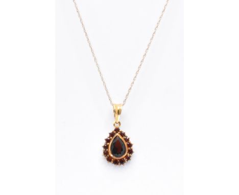 A hallmarked 9ct gold and garnet pendant necklace. The necklace strung with a garnet set pendant strung upon a fine gold chai