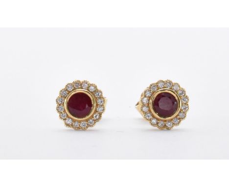 A pair of 18ct gold ruby and diamond stud earrings. The earrings having a central round cut ruby surrounded by a halo of sixt