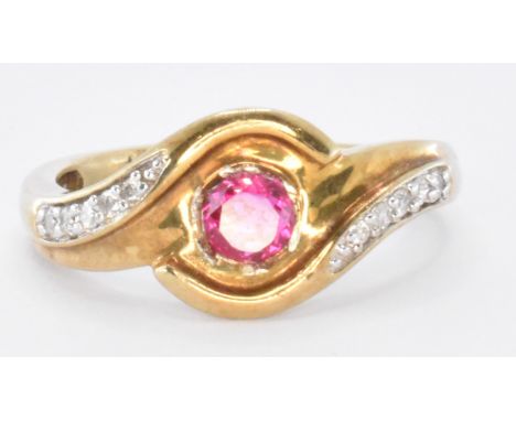 A 14ct gold and ruby cross over ring. The ring set with a central round cut pink / red synthetic ruby with diamond accent sto