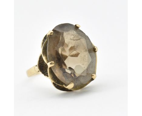 A hallmarked 9ct gold and smokey quartz ring. The ring set with an oval cut smokey quartz within a prong scalloped setting. H