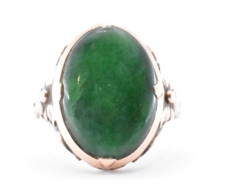 A 9ct gold and nephrite jade ring. The ring being bezel set with an oval nephrite panel with floral moulded shoulders. Chines