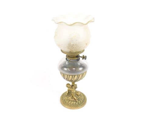 A brass and cut glass oil lamp, of fluted and foliate embossed form, raised on a stem with a putto, flowers and scrolling lea