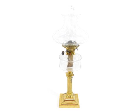 A brass column formed oil lamp, with a cut clear glass reservoir, raised on a stepped square base, with chimney and clear hon