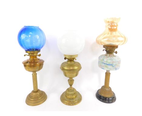 A brass oil lamp, with a mottled glass reservoir, circular black glass socle, with an amber glass shade, 63cm high, together 