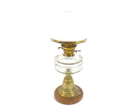 An Art Nouveau brass oil lamp, embossed with festoons of fruit, cut clear glass reservoir, raised on a circular base, with wh