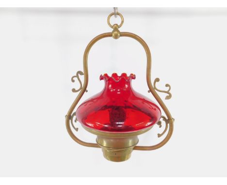 A brass hanging oil lamp, with a dimpled ruby glass shade, 52cm high.