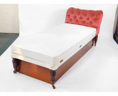 A Victorian mahogany day bed, upholstered in red button back draylon, with an under storage box and mattress, raised on turne