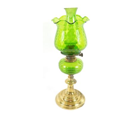 A brass oil lamp, of turned circular form, with a green glass reservoir, chimney and frilled shade, 52.5cm high.