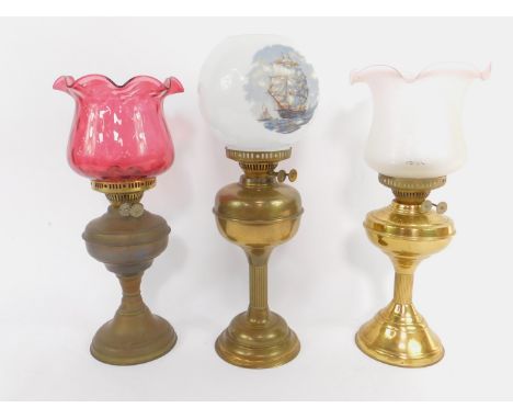 A brass oil lamp, with a frosted and etched glass shade, 47cm high, and two further brass oil lamps, one with a globular shad