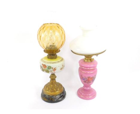 A duplex brass oil lamp, with embossed decoration, opaline glass reservoir painted with flowers, raised on a black circular g