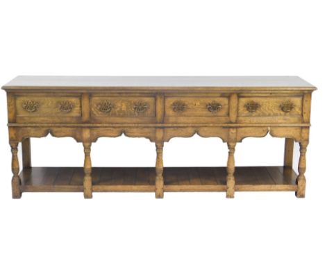 A Georgian style oak dresser, with four drawers over a shaped apron, raised on baluster turned columns and block feet, united