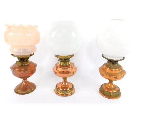 A near pair of copper and brass oil lamps, with white globular glass shades, and a further copper and brass oil lamp with a p