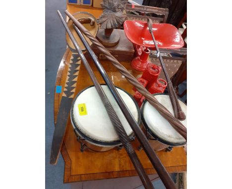 A vintage lot comprising treen tribal wall masks, a red enamelled scales, treen items, walking sticks, bongo drums and other 
