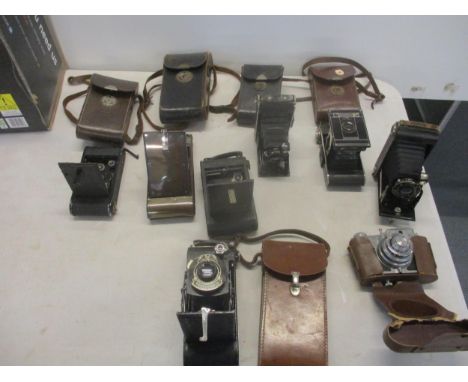 A collection of mainly vintage folding film cameras in leather cases to include an Ensign Carbine tropical model with Compur 