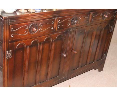 ERCOL STAINED OAK "TUDOR" DINING SUITE
comprising a the sideboard with three short drawers over two cupboards, an extending d