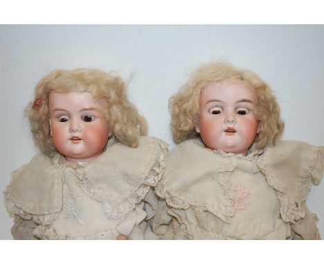 A pair of Armand Marseille Flora-Dora bisque head dolls, having rolling brown eyes and open mouth with four top teeth showing