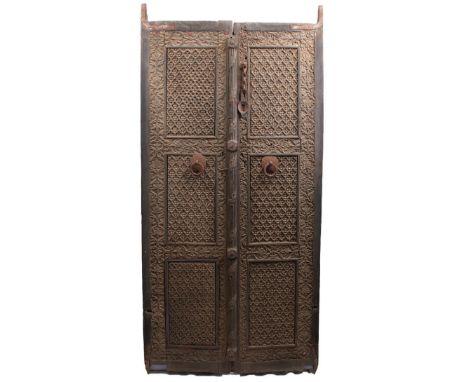 A PAIR OF 17TH CENTURY MUGHAL INDIAN CARVED HARDWOOD DOORS, each with three panels of flowerheads, surrounded by further pane