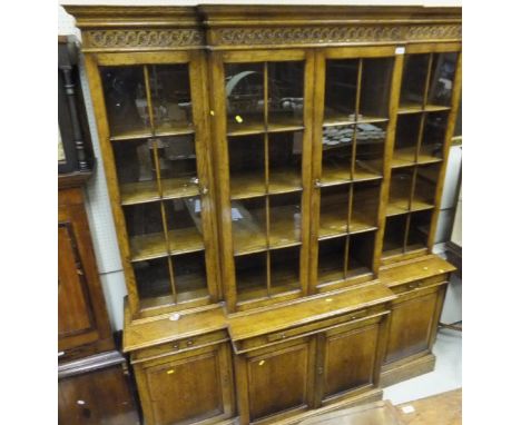 A modern oak breakfront bookcase, the upper section with four glazed and barred doors enclosing adjustable shelving, over a c