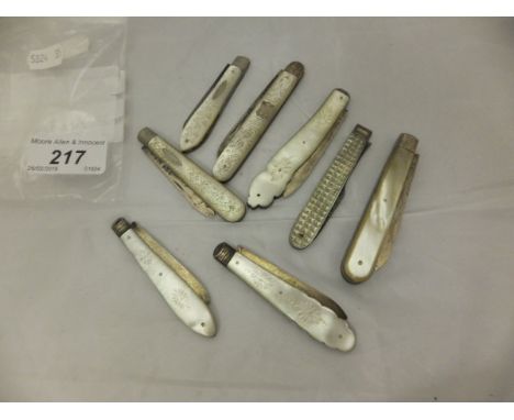 A collection of seven mother of pearl and silver bladed folding fruit knives together with a mother of pearl and silver prong