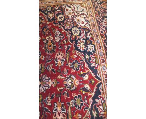 A Kashan carpet, the central floral medallion in pale blue, red, cream and dark blue on a red floral decorated ground within 