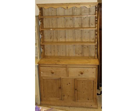 A Victorian pine dresser, the top with three tier plate rack above two drawers and two cupboard doors, raised on a plinth bas