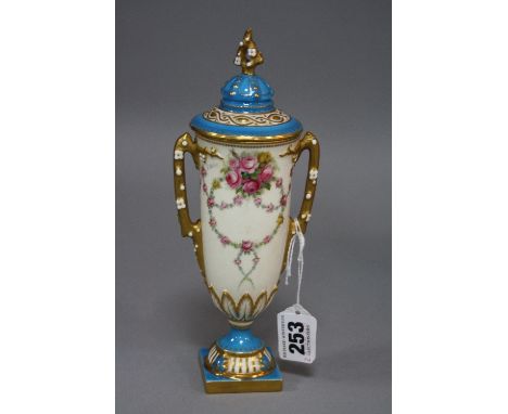 A ROYAL WORCESTER PEDESTAL VASE AND COVER, the urn body hand painted with floral swags, signed E Phillips, naturalistic bloss